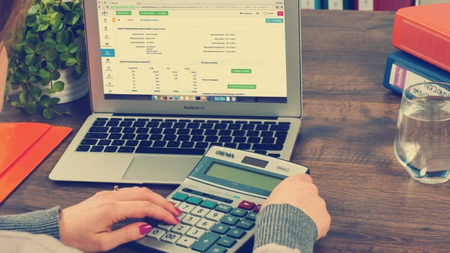 Kobieta siedzy przy laptopie i oblicza podatek na kalkulatorze